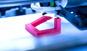 Un technicien contrôle une pièce fraîchement imprimée en 3D au sein d’une PME.